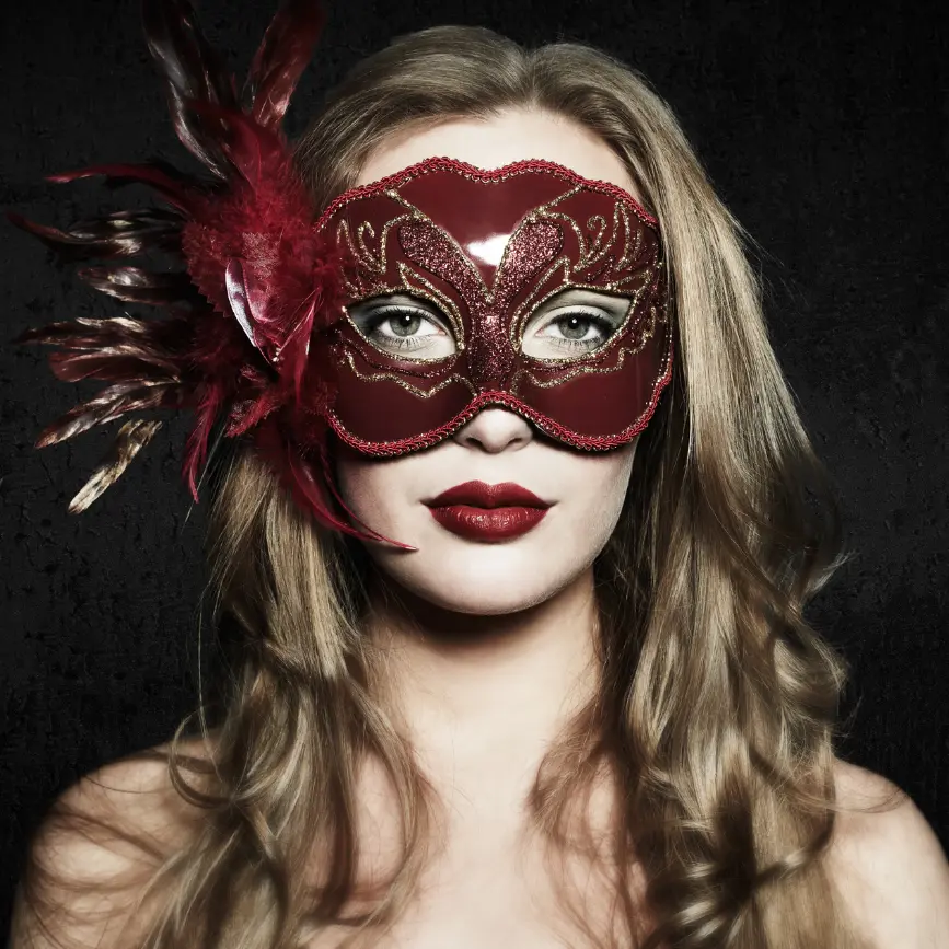 Mujer con máscara veneciana roja y dorada, con detalles de plumas y labios rojos intensos.